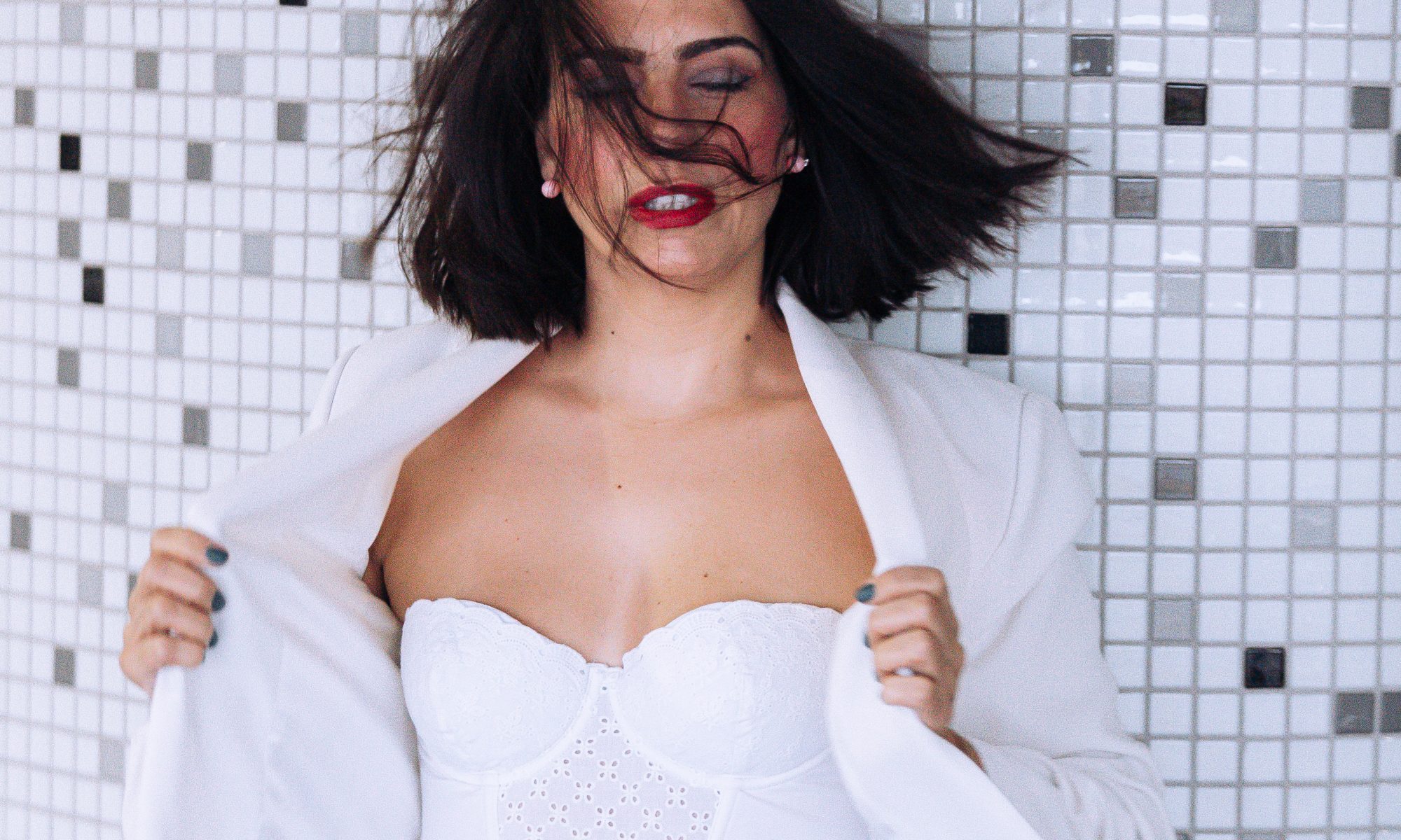 woman with white jacket body and blue jeans with her eyes closed with open arms