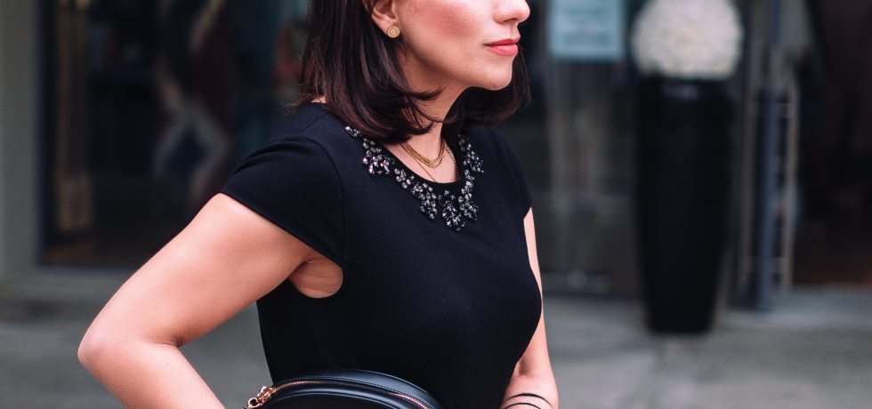 woman dressed with a litle black dress with a black bag in her hands